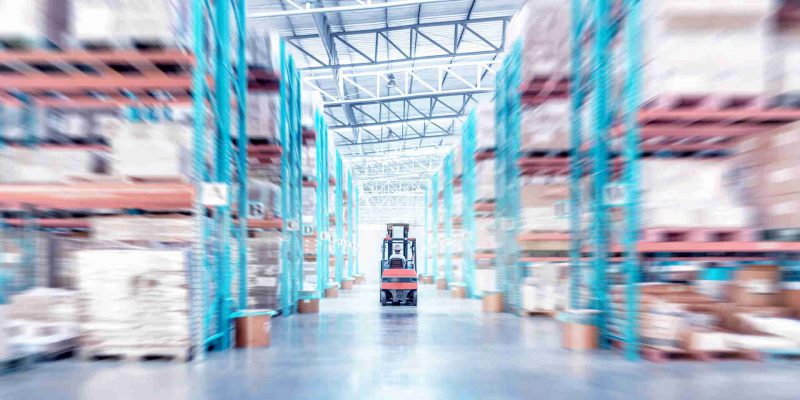 warehouse metal structure interior with  forklift truck in selective focus, rows of merchandise shelves with goods container boxes