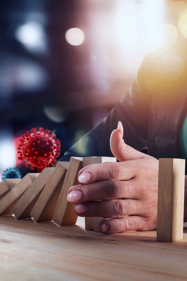 covid19brt-2-dominos Businesswoman stops a chain fall by viruses like domino game toy. Concept of preventing crisis and failure in business